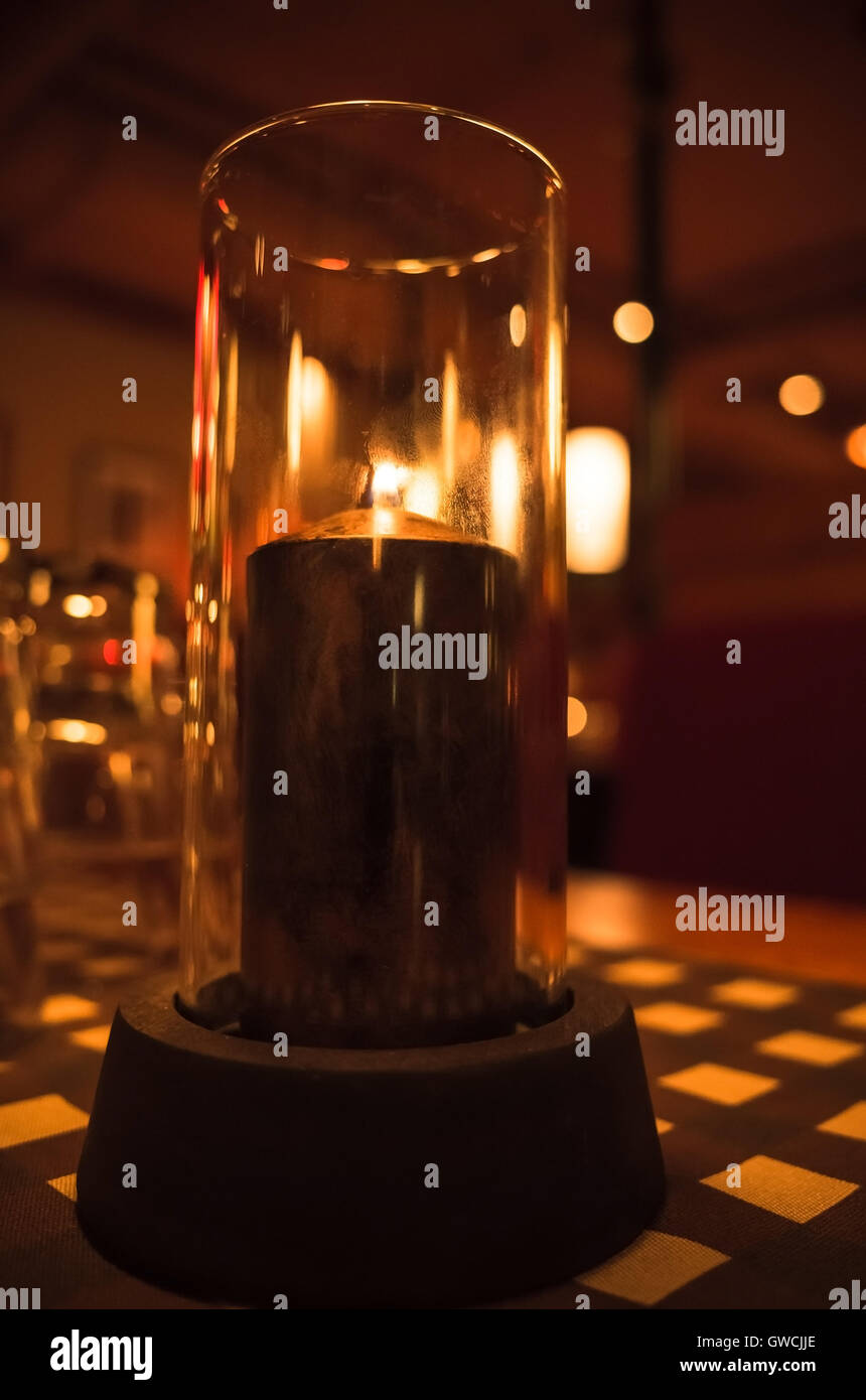 Kerze brennt in Leuchter aus Glas auf Tisch im Dunkelrestaurant gemacht. Nahaufnahme Foto mit. selektiven Fokus Stockfoto