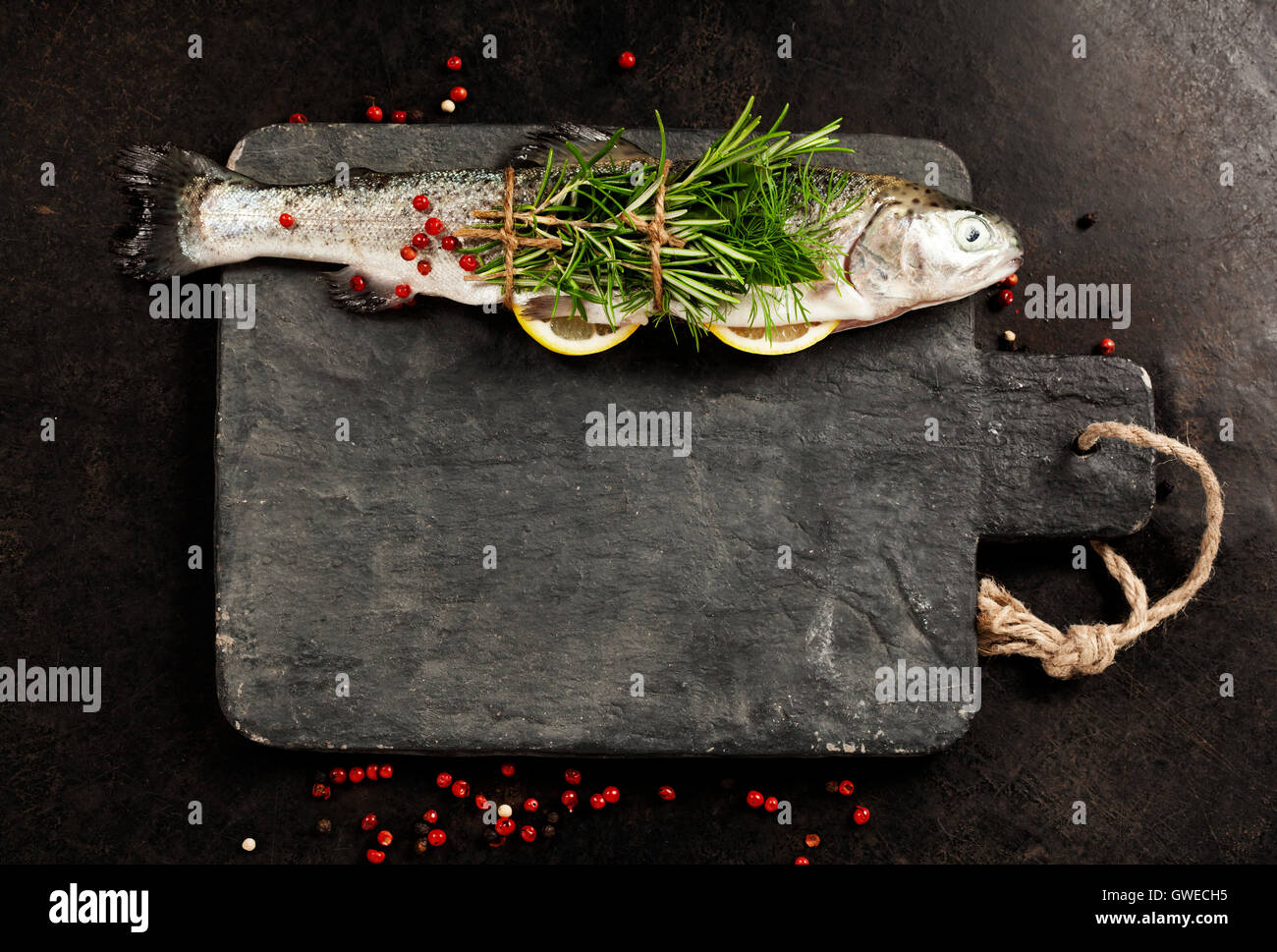 Rohe Forelle mit Zitrone, Kräutern und Gewürzen auf rustikalen Hintergrund Stockfoto