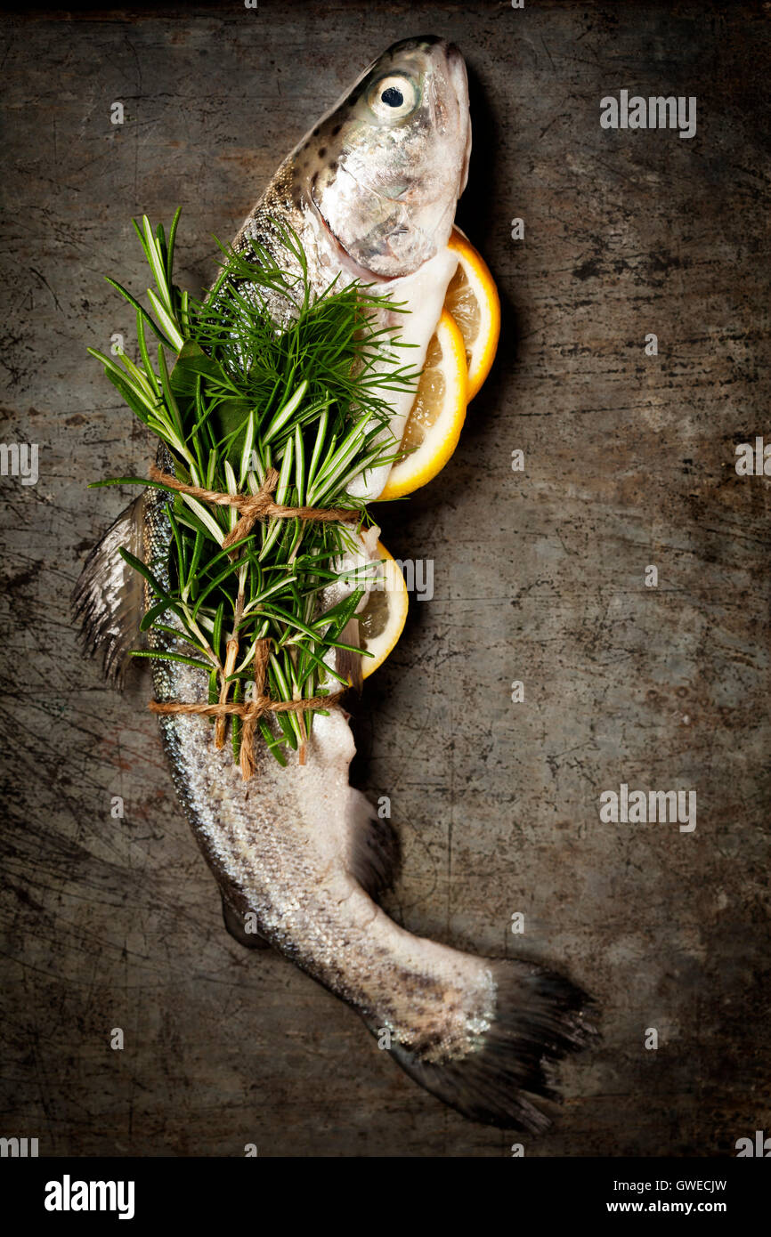 Rohe Forelle mit Zitrone, Kräutern und Gewürzen auf rustikalen Hintergrund Stockfoto