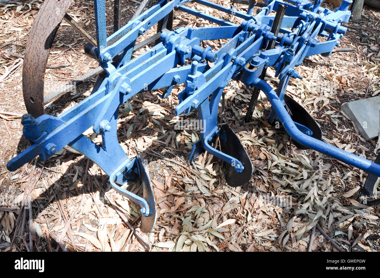 Nahaufnahme eines alten blauen Metall Bauernhofes Bodenbearbeitung Maschinen mit Messern und verrosteten Teilen auf Outdoor-Boden getrocknet Blattoberfläche. Stockfoto