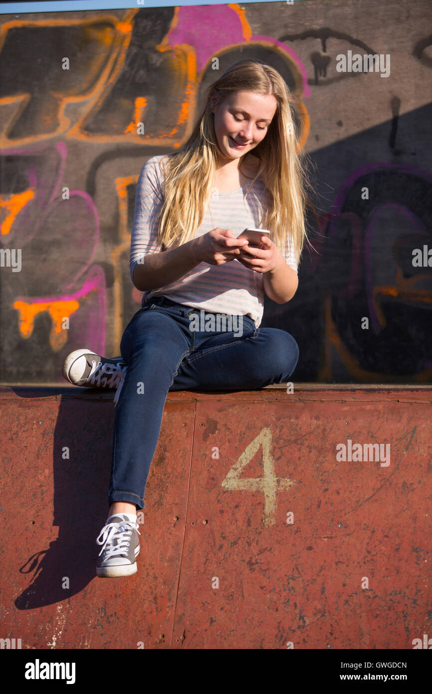 Teenager-Mädchen SMS auf Handy auf Spielplatz Stockfoto