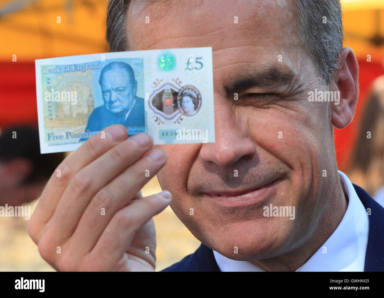 Der Gouverneur der Bank of England, Mark Carney, hält eine neue Plastic £5 Note, als er den Whitecross Street Markt in London besucht. Stockfoto