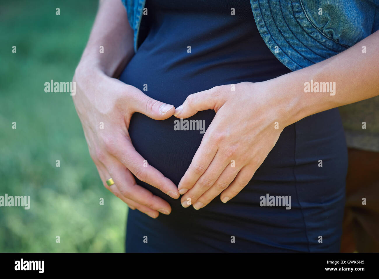 Schwangere Frau Hand in Hand auf ihren Bauch in Form von Herzen Stockfoto