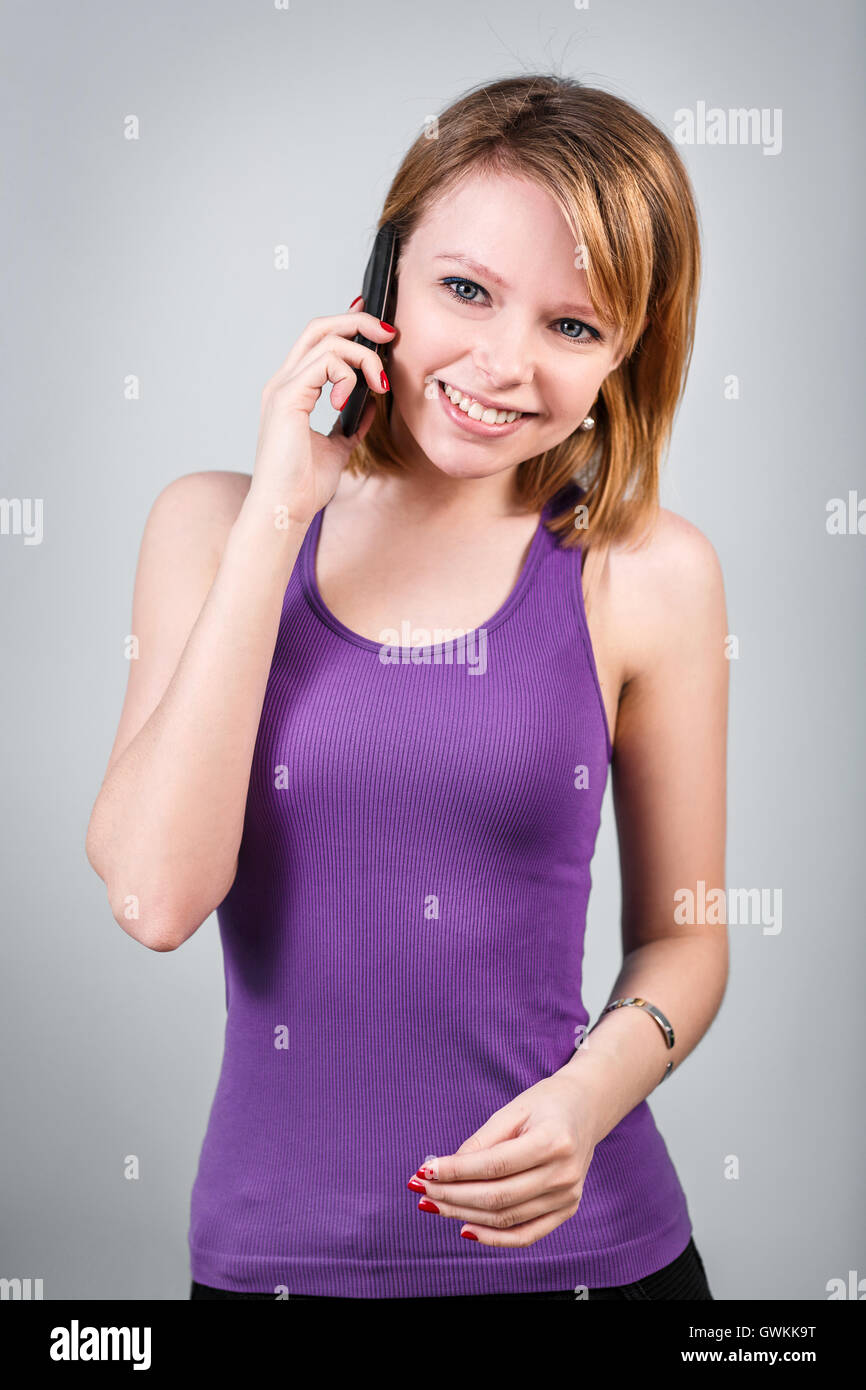 Junge schöne Frau spricht am Telefon auf den grauen Hintergrund Stockfoto