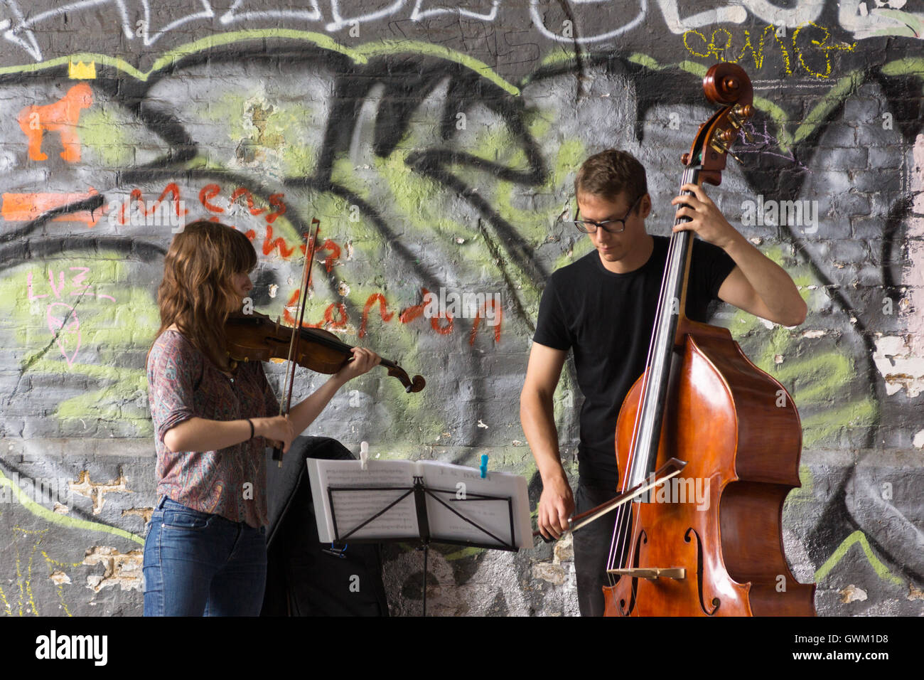 Ein paar Musiker als Straßenmusikant unter einer Eisenbahnbrücke auf Clink Street, London Stockfoto