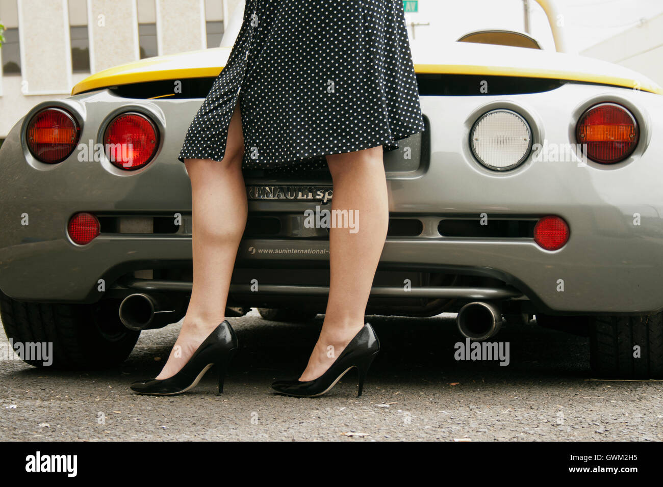 Weibliche stehen hinter einem Sportwagen Stockfoto