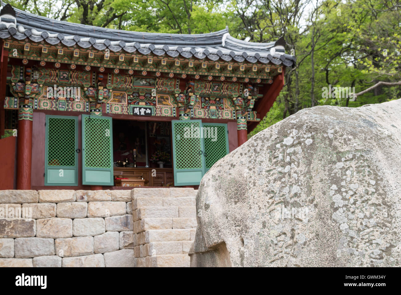 Reich verzierte Gebäude hinter einem Felsen mit Gravuren am Beomeosa Tempel in Busan, Südkorea. Konzentrierte sich auf den Felsen. Stockfoto