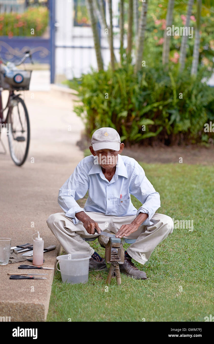 Messerschleifer. 75-jähriger älterer Mann bei der Arbeit, der Haushaltsgeräte schärft. Thailand S. E. Asien Stockfoto