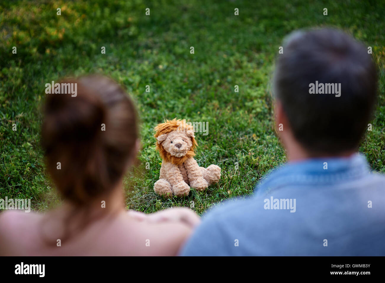 Liebe paar sitzen auf dem Rasen und schauen Sie sich das Spielzeug-Löwe Stockfoto