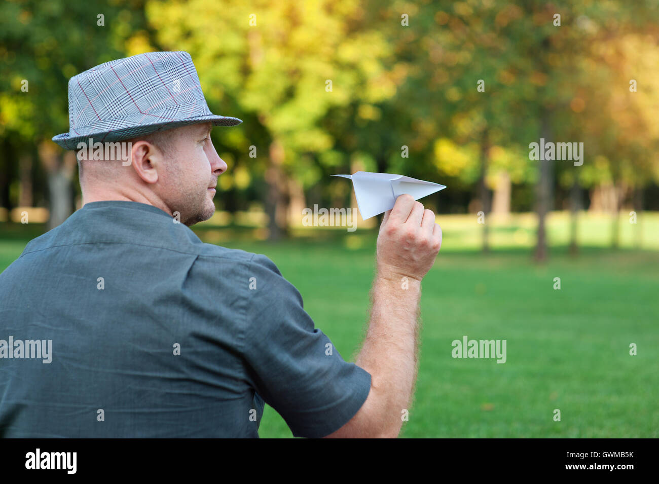 Mann mit einem Papierflieger in der Hand auf Wiese Stockfoto