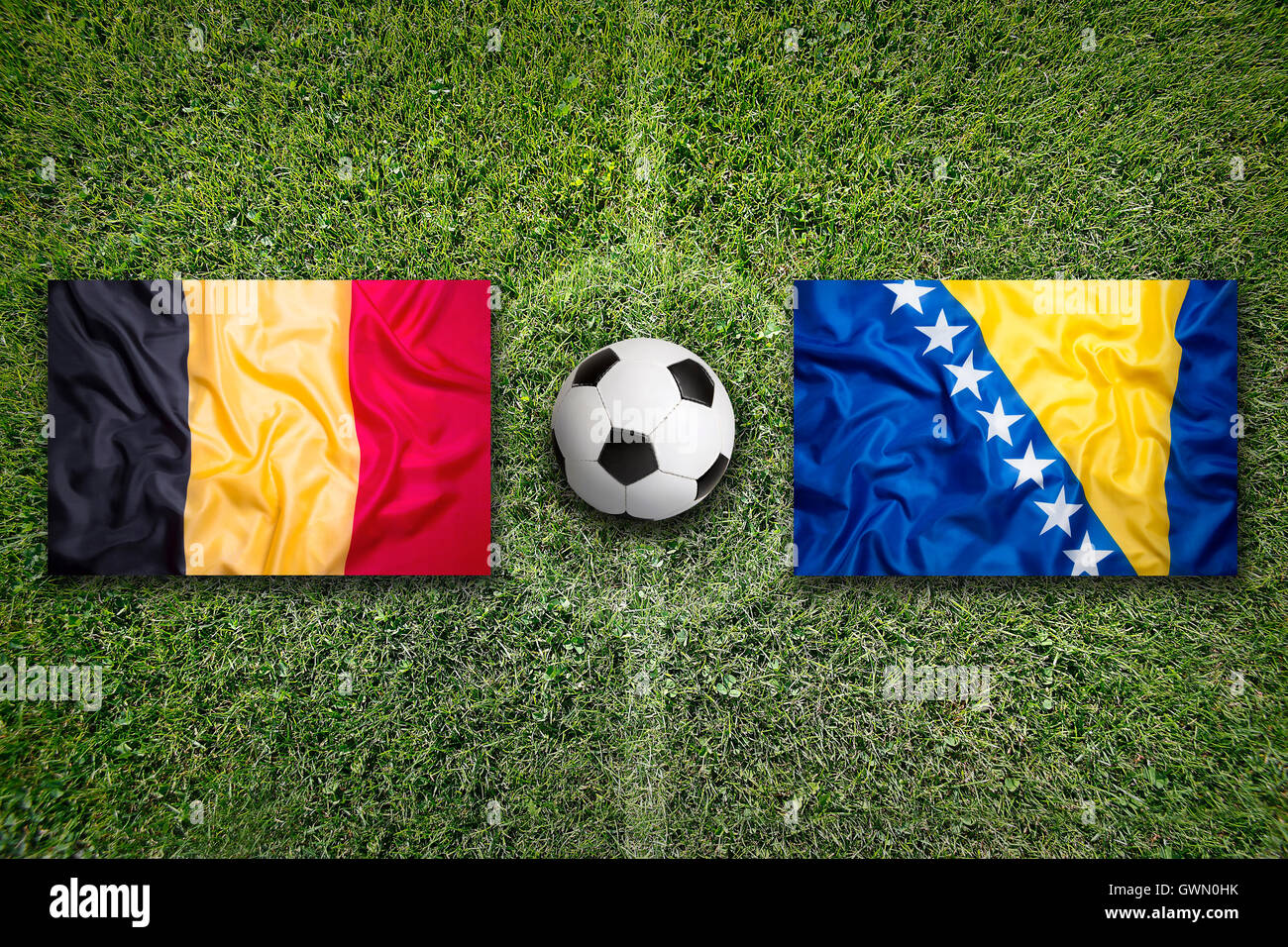 Belgien und Bosnien und Herzegowina Flaggen auf einem grünen Fußballfeld Stockfoto