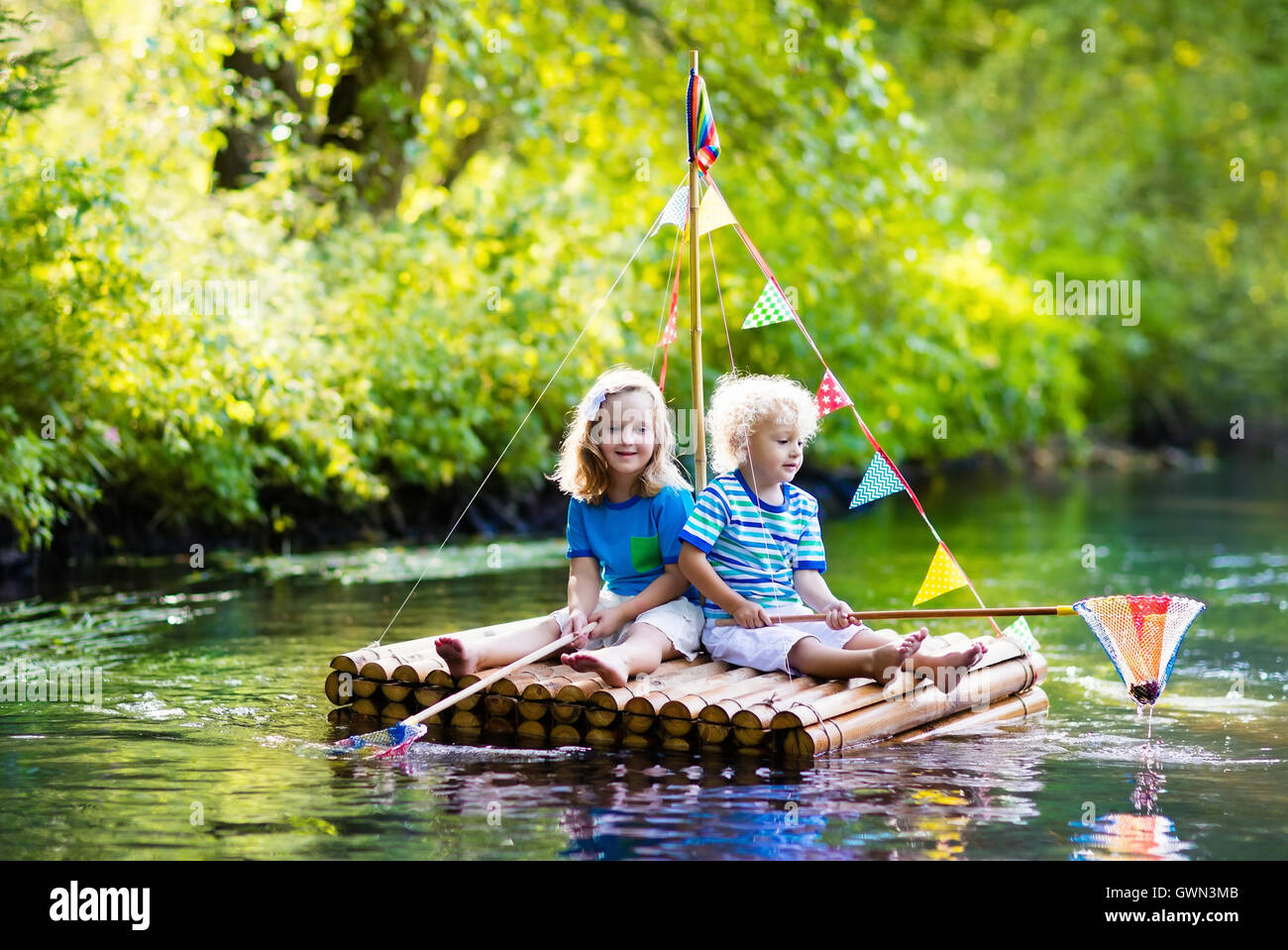 Zwei Kinder auf hölzerne Floß Fang von Fischen mit einem bunten Netz in einem Fluss und das Spiel mit Wasser am heißen Sommertag. Stockfoto