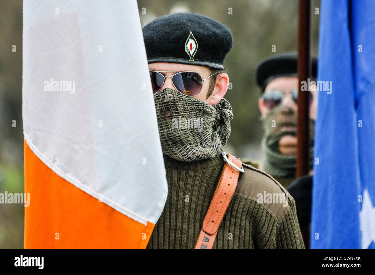 Mann in einem paramilitärischen einheitliche, einschließlich Beret, Sonnenbrille, Gesicht scrim und Armee militärische Jumper nimmt Teil an ein Ostern Steigende commemorative März von der Irish Republican Socialist Party. Stockfoto