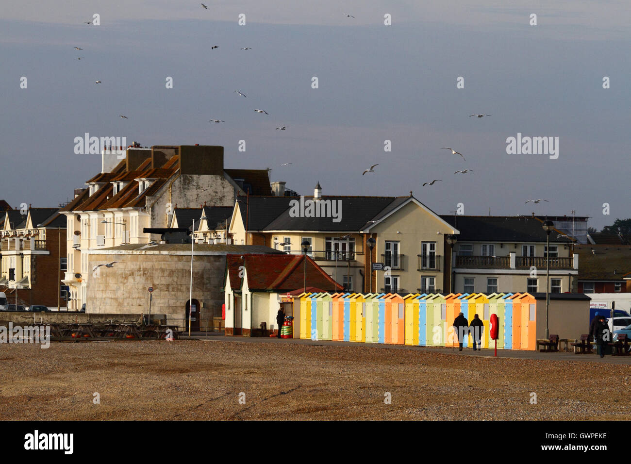 Menschen zu Fuß vorbei an Linie der hölzernen Umkleidekabinen am Meer auf eine Winter-Nachmittag, Seaford, East Sussex, England Stockfoto