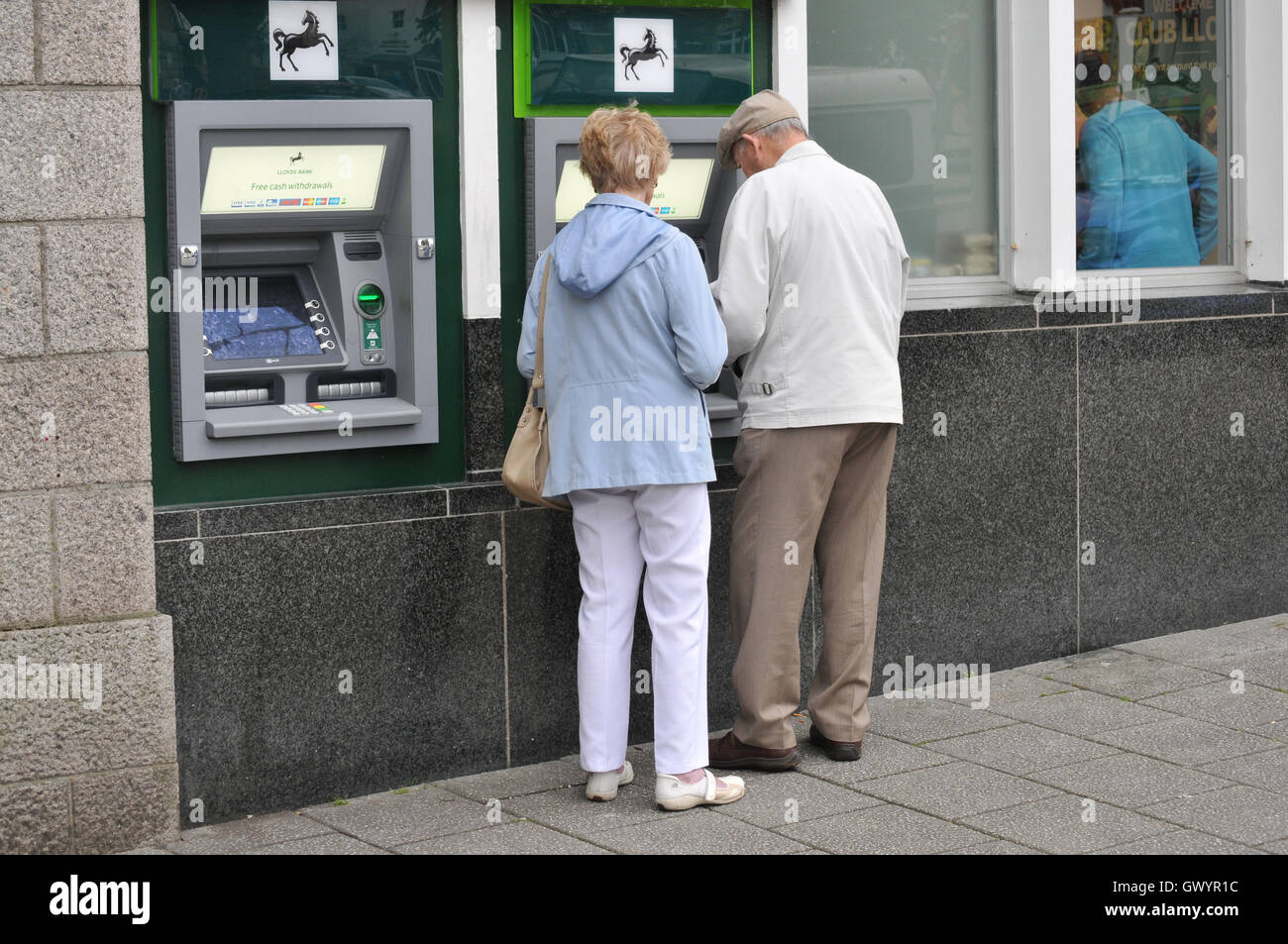 Zwei Rentner an einem Geldautomaten in Falmouth, Cornwall Stockfoto