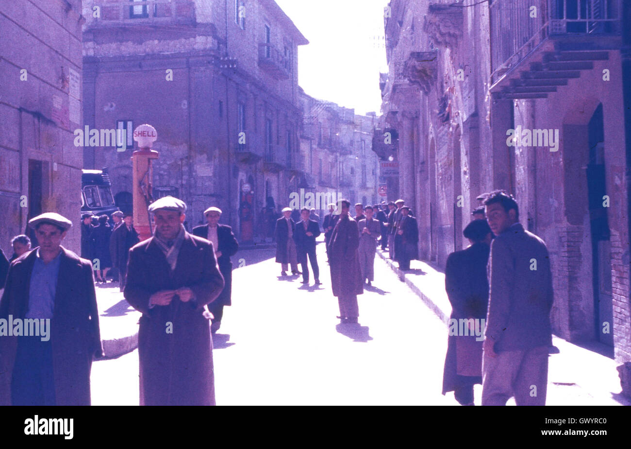 1951, historisches, Wandern nach dem Weltkrieg 11 und arbeitslosen Männern durch eine Straße in der Stadt Gela, Sizilien, Italien. Stockfoto