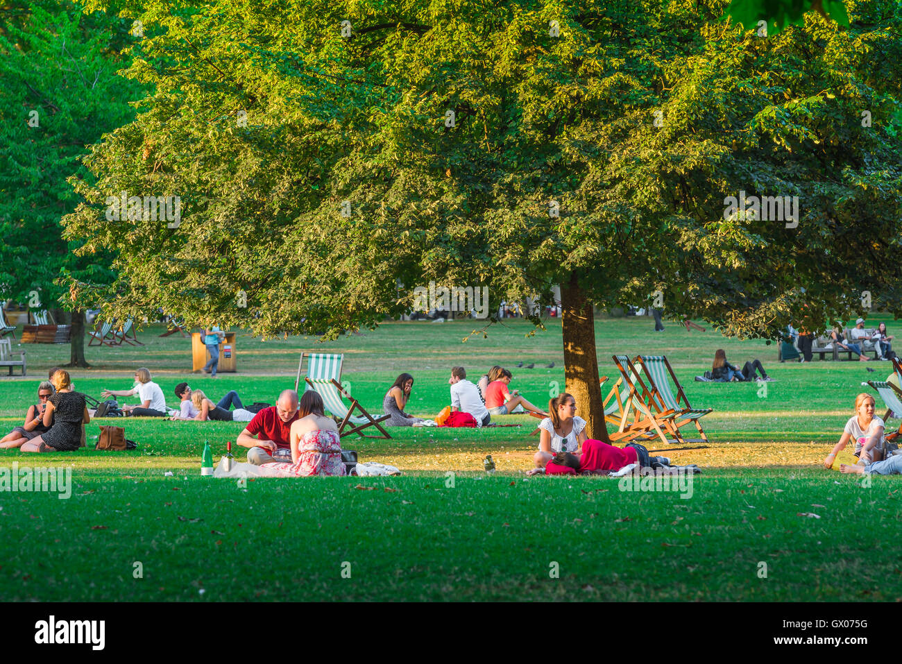 Die Menschen parken den Sommer, Blick auf Menschen, die sich an einem warmen Sommerabend im St James's Park, im Zentrum von London, England, Großbritannien, entspannen. Stockfoto