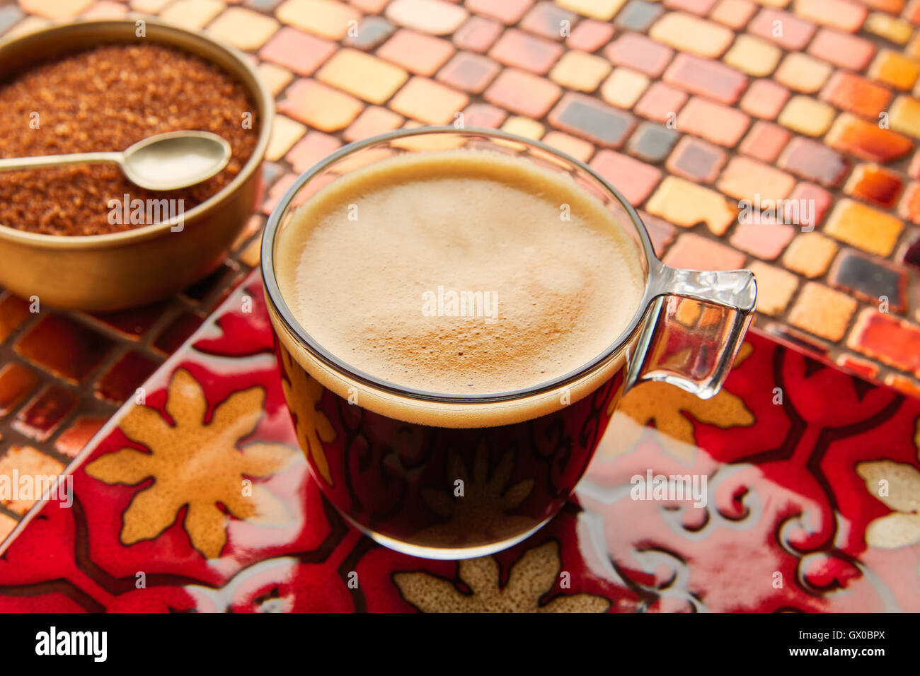 Kaffee Glasschale mit Sahne auf Fliesen rot braun goldenen Tisch Stockfoto