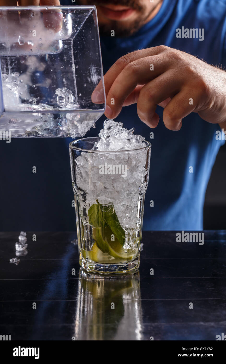 Barkeeper gebrochenes Eis in ein Glas setzen Stockfoto