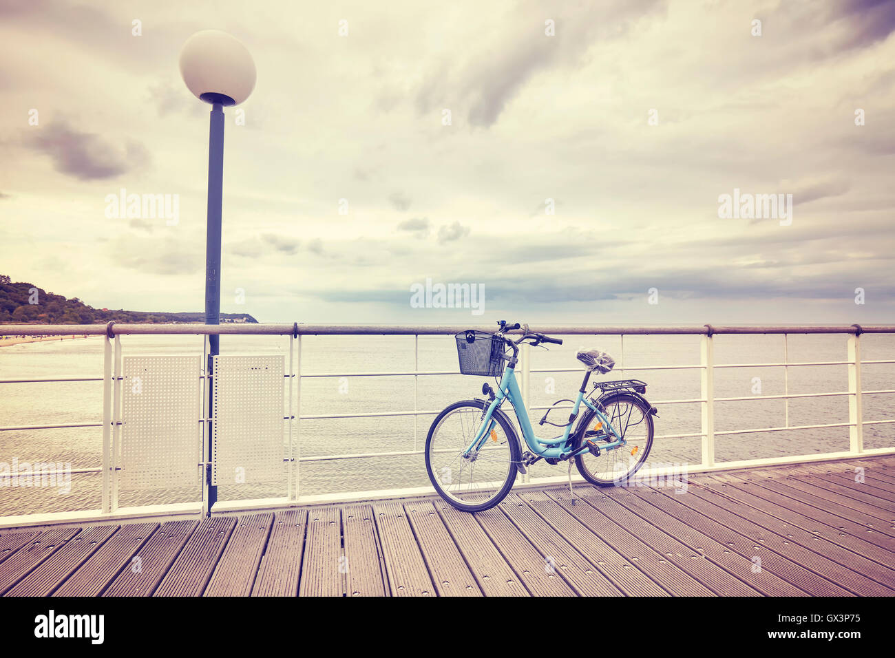 Vintage getönten einsam Fahrrad mit Korb auf leeren Pier, verregneten Sommertag. Stockfoto