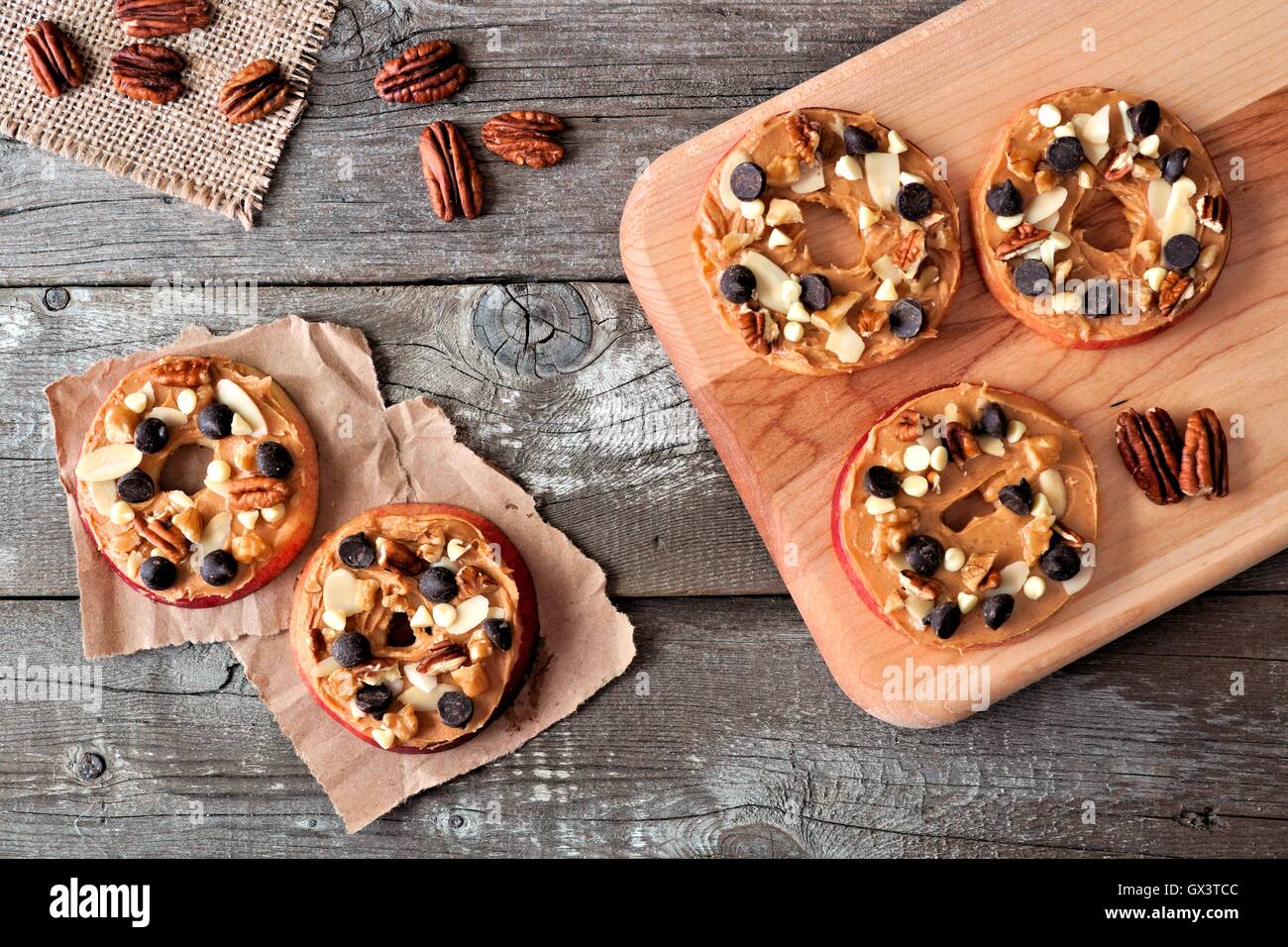 Im Herbst Apfel rundet mit Erdnussbutter, Schokolade-Chips und Nüssen, nach unten gerichtete Blick auf rustikalen Holz Stockfoto