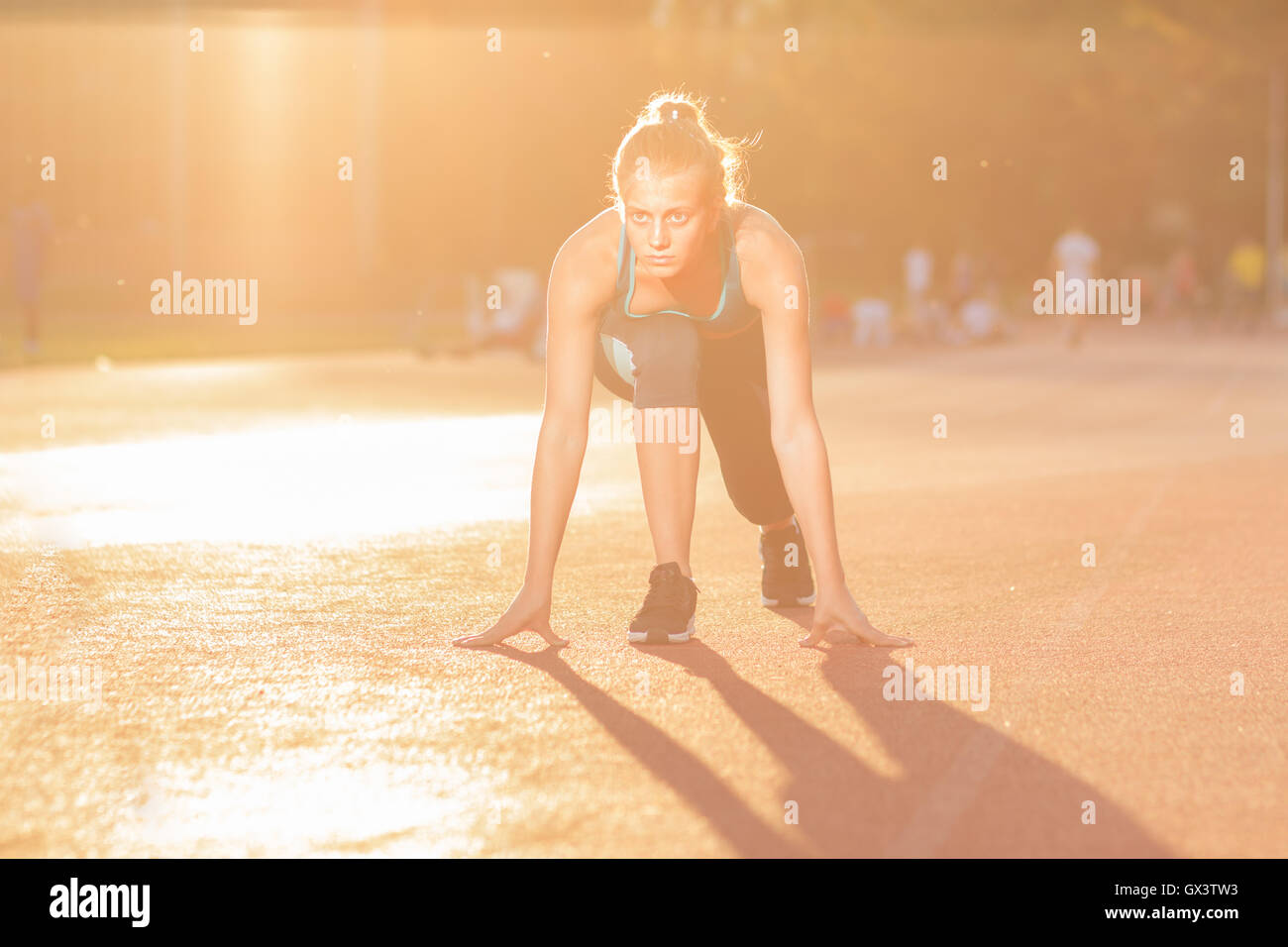 junges Mädchen Teenager Sprinter Start Position im freien sonnigen Tag Blendenfleck Stockfoto