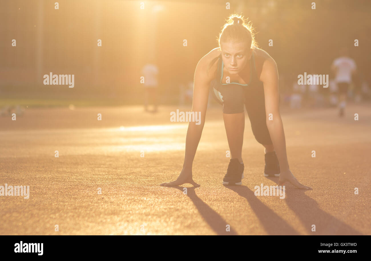 junges Mädchen Teenager Sprinter Start Position im freien sonnigen Tag Blendenfleck Stockfoto