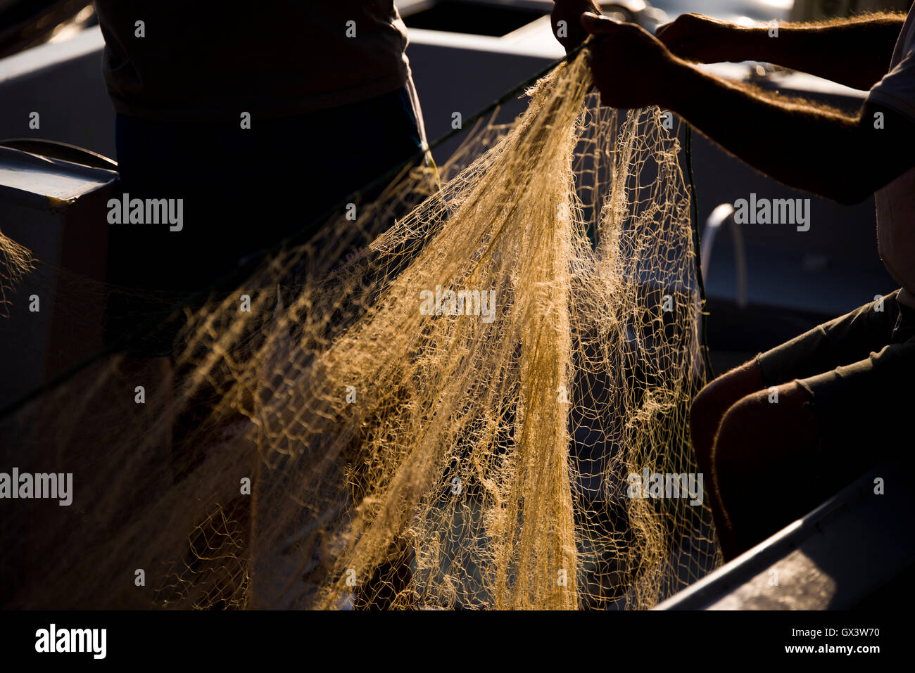 Fischernetz mit schönen Sonnenlicht und ein Mann mit seinen Händen festhält. Stockfoto