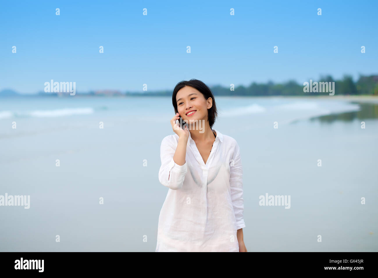 Asiatin auf einen Strandurlaub am Telefon sprechen Stockfoto