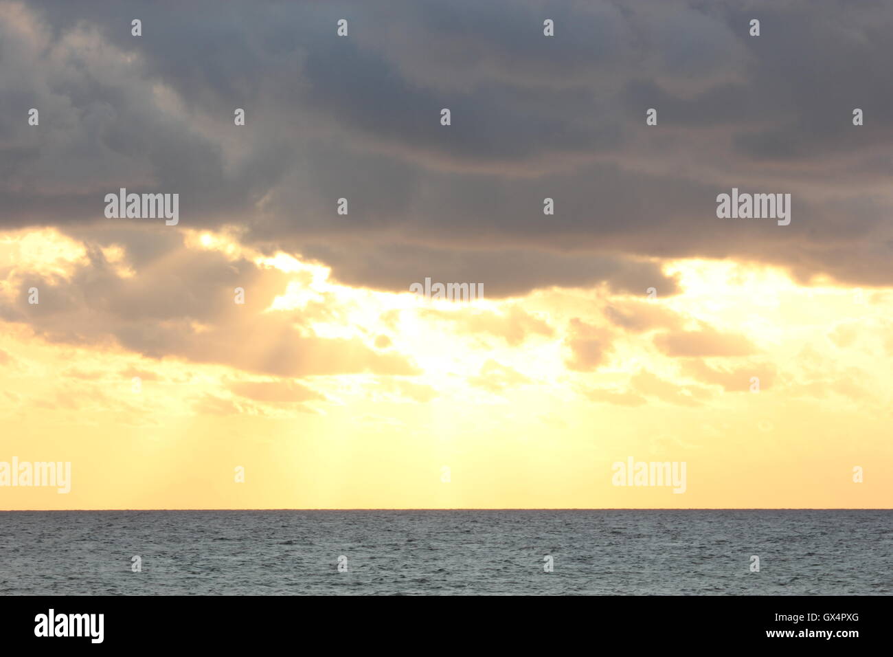 Ein wunderschön Moody Himmel mit der Sonne hinter den Wolken, bei Sonnenuntergang, mit dem Meer Stockfoto