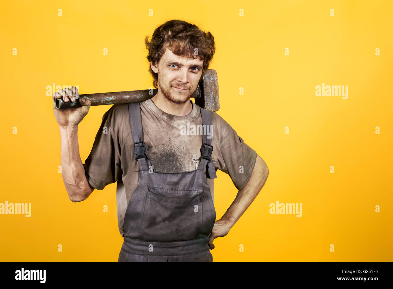 Gut aussehend lächelnd Mechaniker Hammer gelb schmutzig Stockfoto