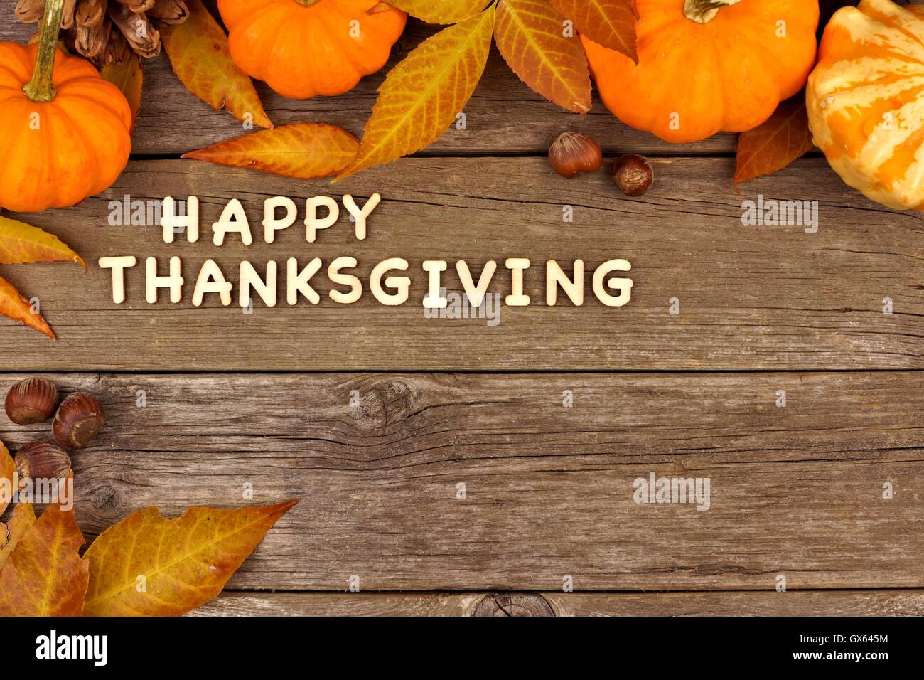 Happy Thanksgiving Holzbuchstaben mit einer herbstlichen Kürbis und Blätter Ecke Grenze gegen Altholz Stockfoto
