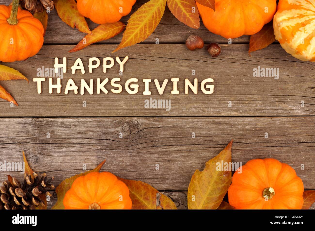 Happy Thanksgiving Holzbuchstaben mit einer herbstlichen Kürbis und Blätter Doppelrand gegen altes Holz Stockfoto