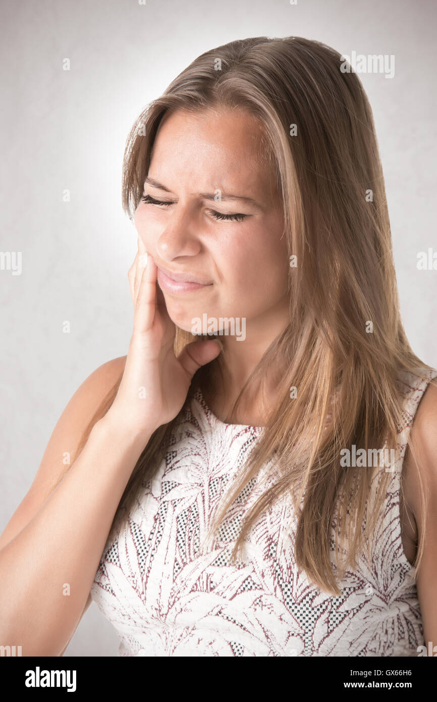 Frau mit einem Zahn Schmerzen isoliert in grau Stockfoto