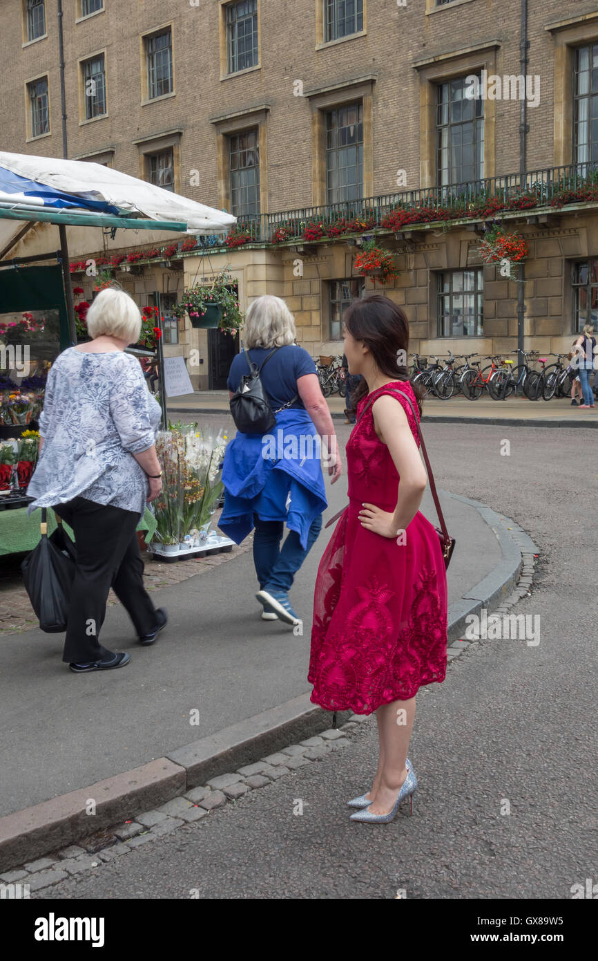 Schlanke junge orientalische Frau im roten Kleid die Hände auf die Hüften Markt Hill Cambridge Stadt England 2016 Stockfoto