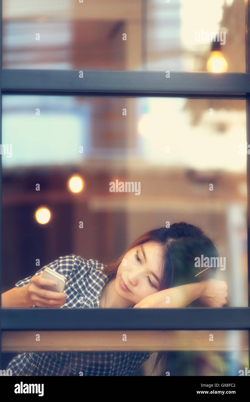 Asia Frau sitzt am Tisch und SMS mit ihrem Handy Urlaub Konzept. Stockfoto