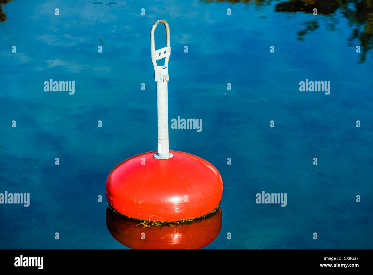 Eine rote Boje im ruhigen blauen Wasser festmachen. Stockfoto