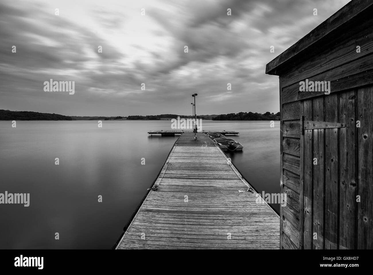 Landschaftsbild der schönen bei Sonnenuntergang von Freizeitbooten vertäut am Steg im See am Ende der Sommertag in schwarz / weiß Stockfoto
