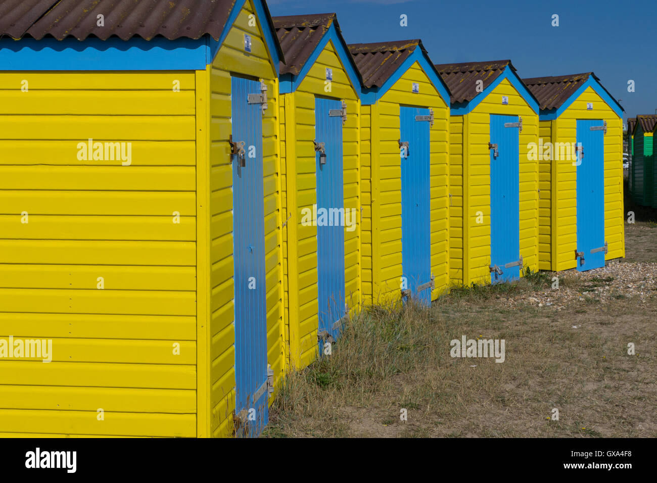 Reihe von gelben Strand Strandhütten mit blauen Türen Stockfoto