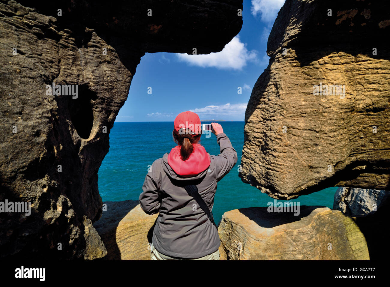 Portugal: Frau nehmen Momentaufnahme der Blick auf das Meer mit Smartphone durch ein Naturstein-Fenster Stockfoto