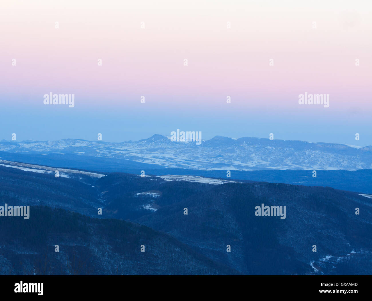 Wintermorgen in den Bergen in Arkhyz (Russland) mit Pisten fallenden Schnee und blau und rosa Himmel als Hintergrund. Stockfoto
