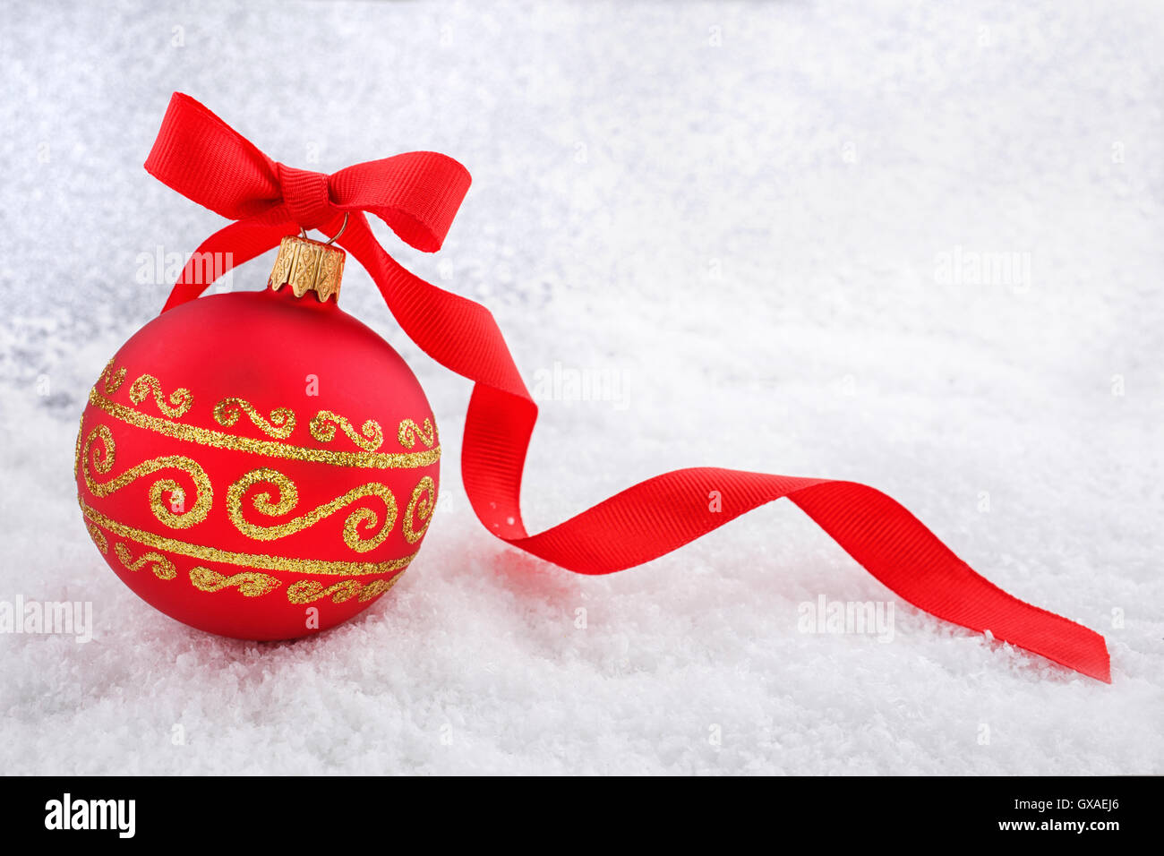 Rote Weihnachtskugel mit Band im Schnee Stockfoto