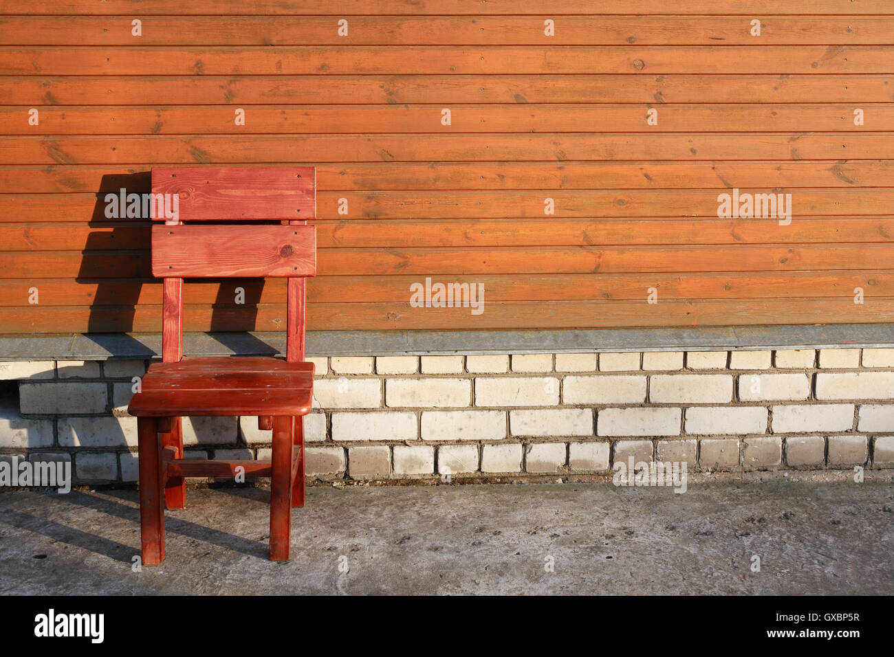 Zeit für Erholung. Roter Stuhl gegen die Holzwand des Hauses Stockfoto