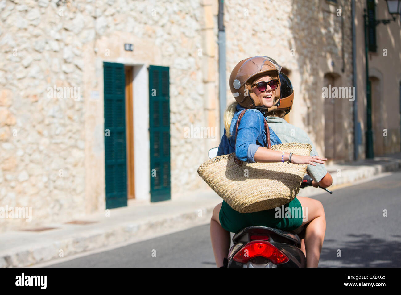 Junge Frau Reiten Sozius durch Dorf rückblickend, Mallorca, Spanien Stockfoto