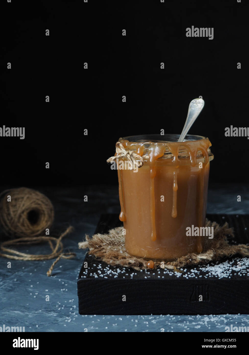 Hausgemachte gesalzenem Karamell-Sauce in einem rustikalen Glas Salz bestreut. Schwarzem Hintergrund Stockfoto