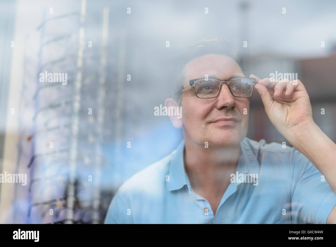 Patienten, die auf der Suche durch eine Brille zum ersten Mal in die Straße von Kleinunternehmen Optiker Stockfoto