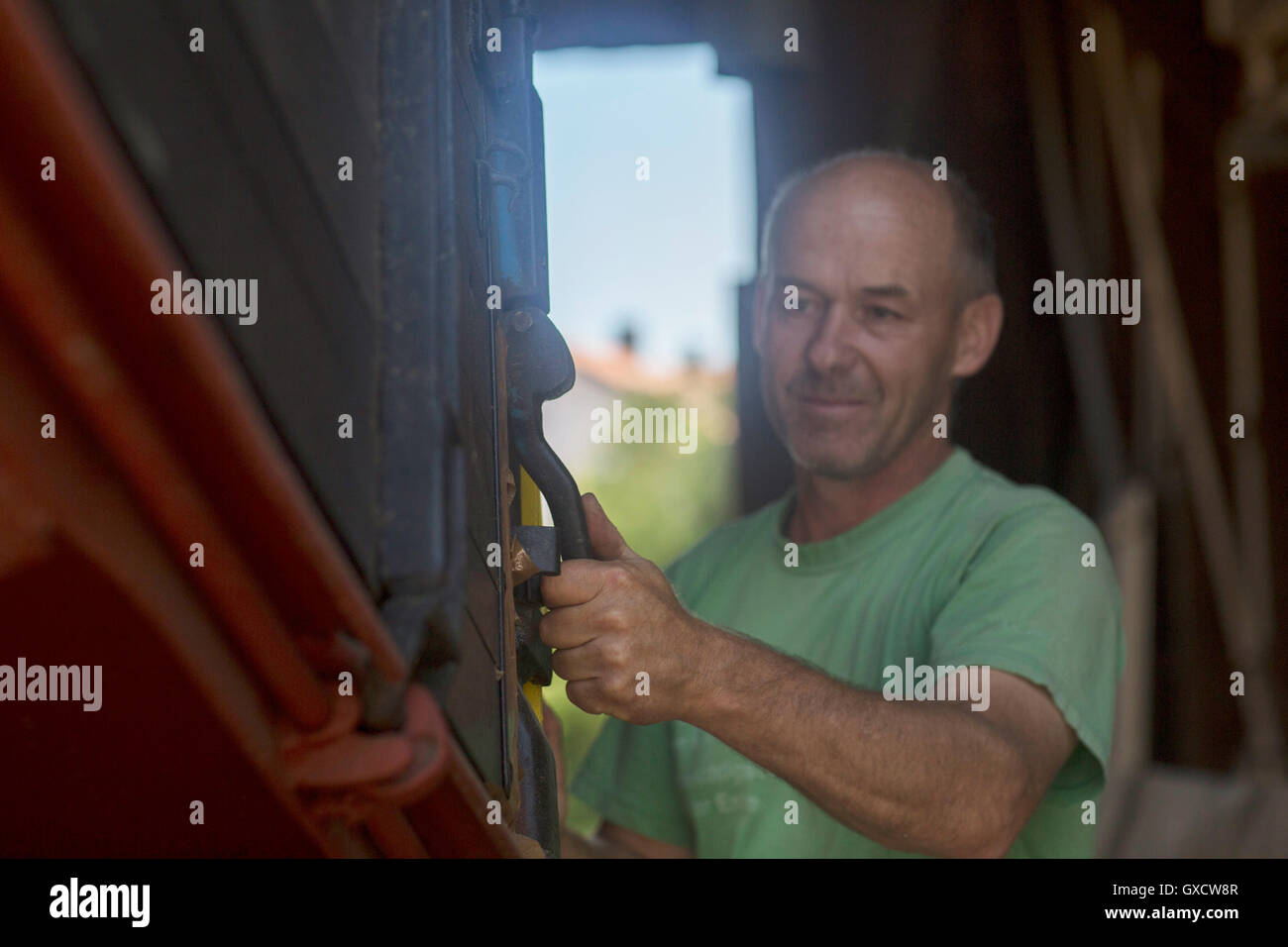 Männliche Landwirt entsperren Trailer im Stall Stockfoto