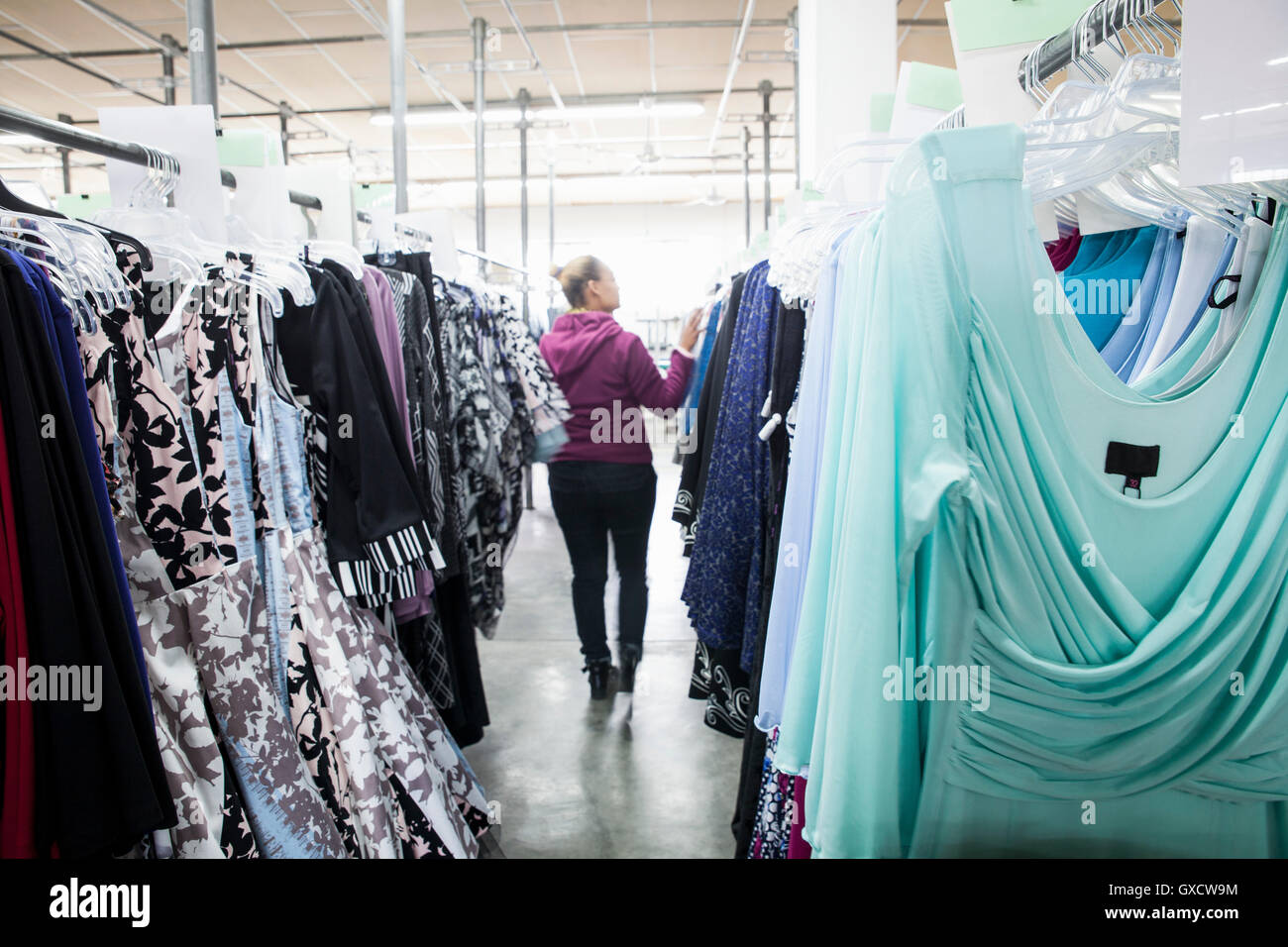 Frau zwischen Kleiderstange in Fabrik Probe Nähstube Stockfoto