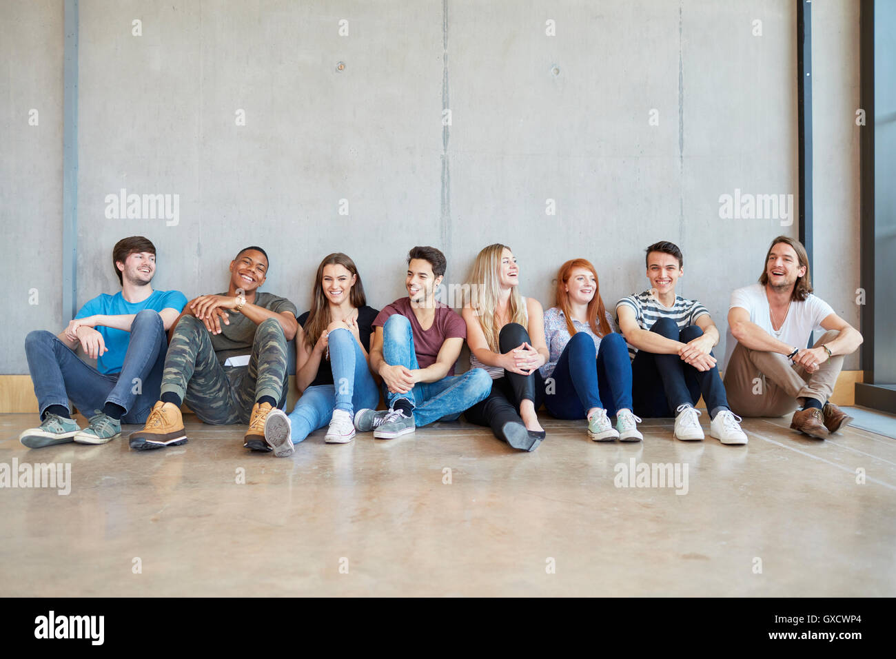 Gruppenbild der Studentinnen und Studenten, die am Boden in einer Reihe am Higher Education college Stockfoto