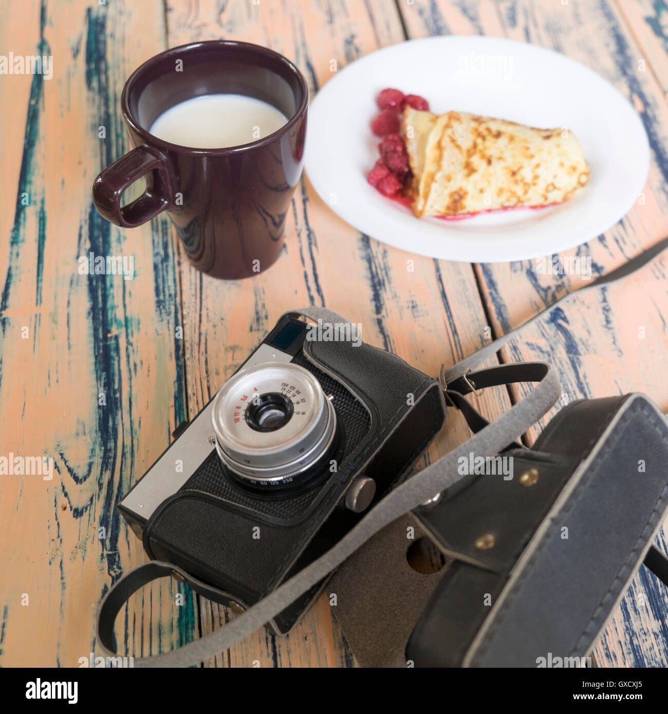 Stillleben mit Kamera, Pfannkuchen Dessert und Tasse Milch Stockfoto